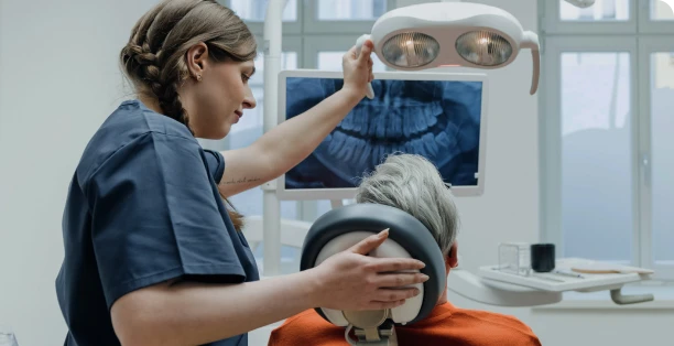 Une dentiste montre à son patient une radiographie de dents.