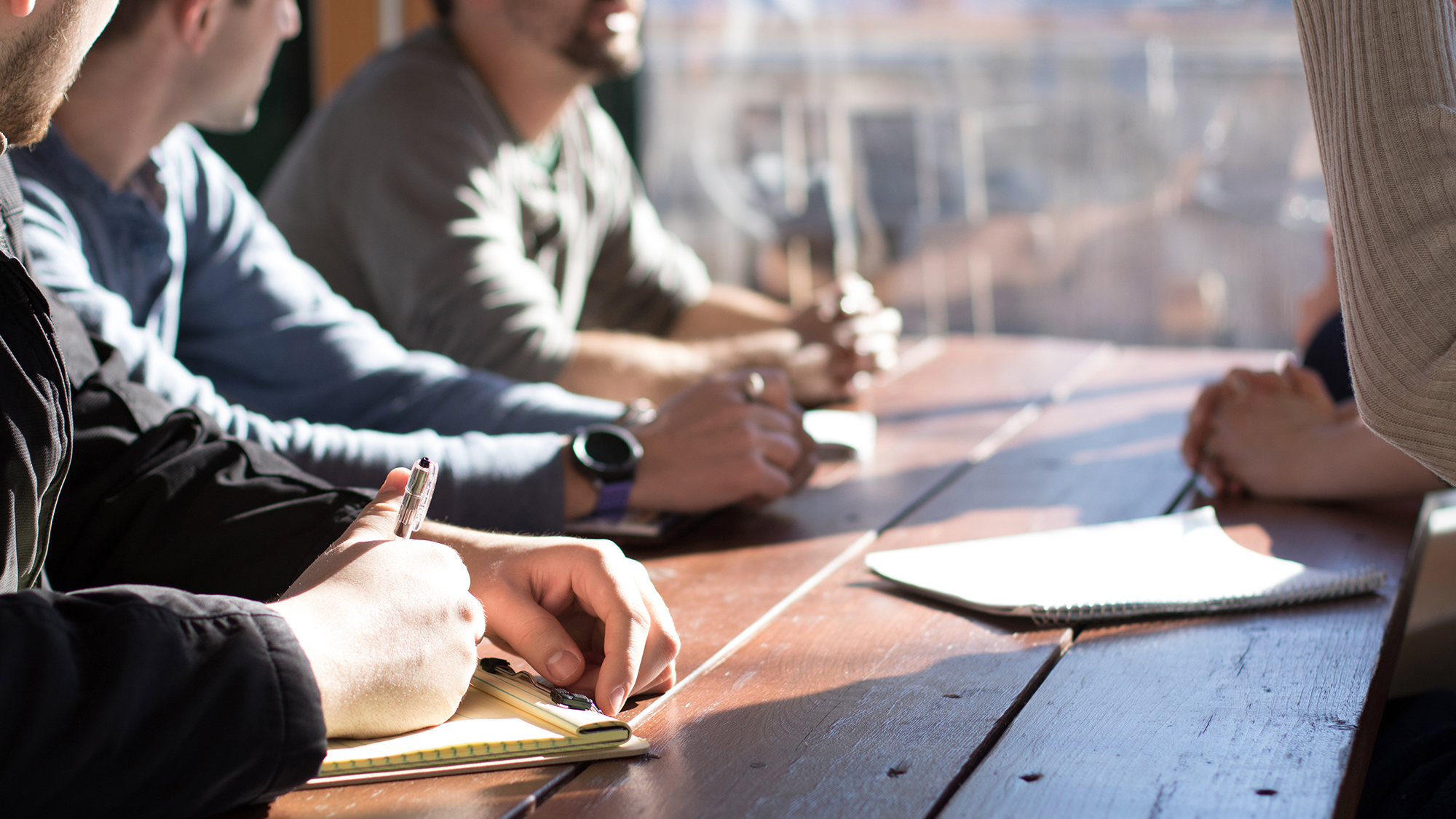 A shot of people at a table taking notes or talking