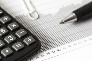 un stylo et une calculatrice posés sur un morceau de papier contenant des informations fiscales
