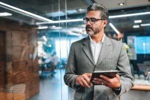 homme d'affaires en veste de sport tenant une tablette dans un bureau