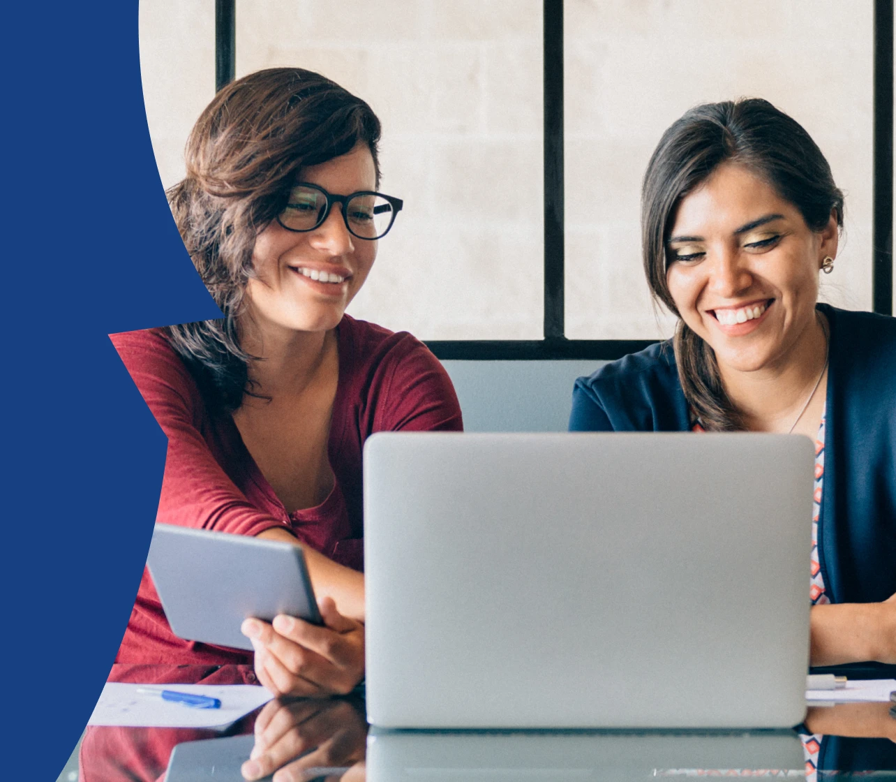 Two women in an office setting looking into a laptop