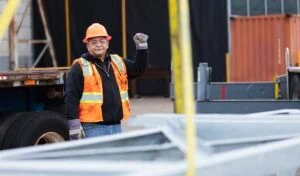 Bauarbeiter steht auf der Baustelle und gibt Kollegen Anweisungen, die schwere Maschinen benutzen