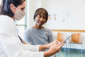 Patient bespricht medizinische Ergebnisse mit einem Arzt, der eine Maske trägt