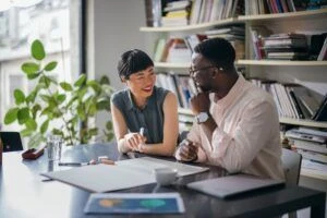 Zwei Mitarbeiter arbeiten an einem großen Schreibtisch in einem Büro zusammen