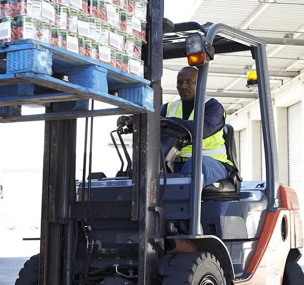 Un travailleur noir conduit un chariot élévateur