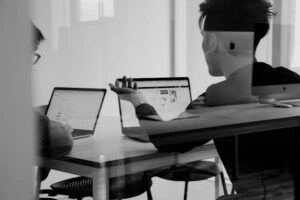 Two workers sitting and working at laptops in a meeting room