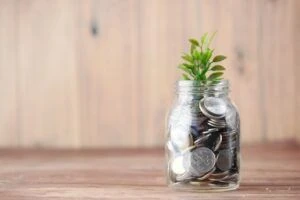 A mason jar filled with coins and a small plant sprouting from the top