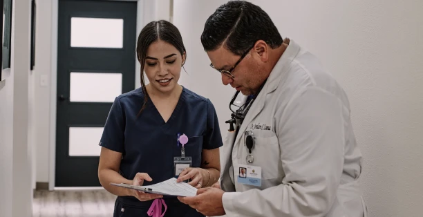 Male dentist in white coat and female dental hygienist looking at paperwork