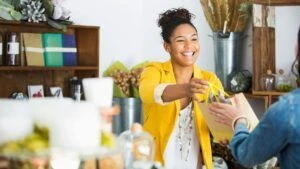 Retail store owner handing paper bag to customer