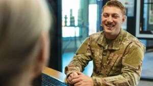A smiling veteran in uniform speaking to another person at a desk