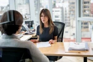 HR manager at her office talking to employee cheerfully while holding some paperwork