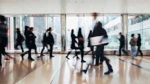 A group of office workers walking in fast motion in a hallway.