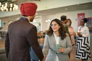 Two people in professional attire shaking hands in a common work space