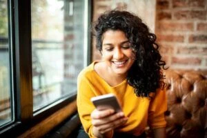 Young Indian woman using mobile phone at the bar