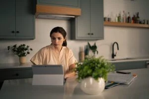 Young woman in home kitchen working on a tablet