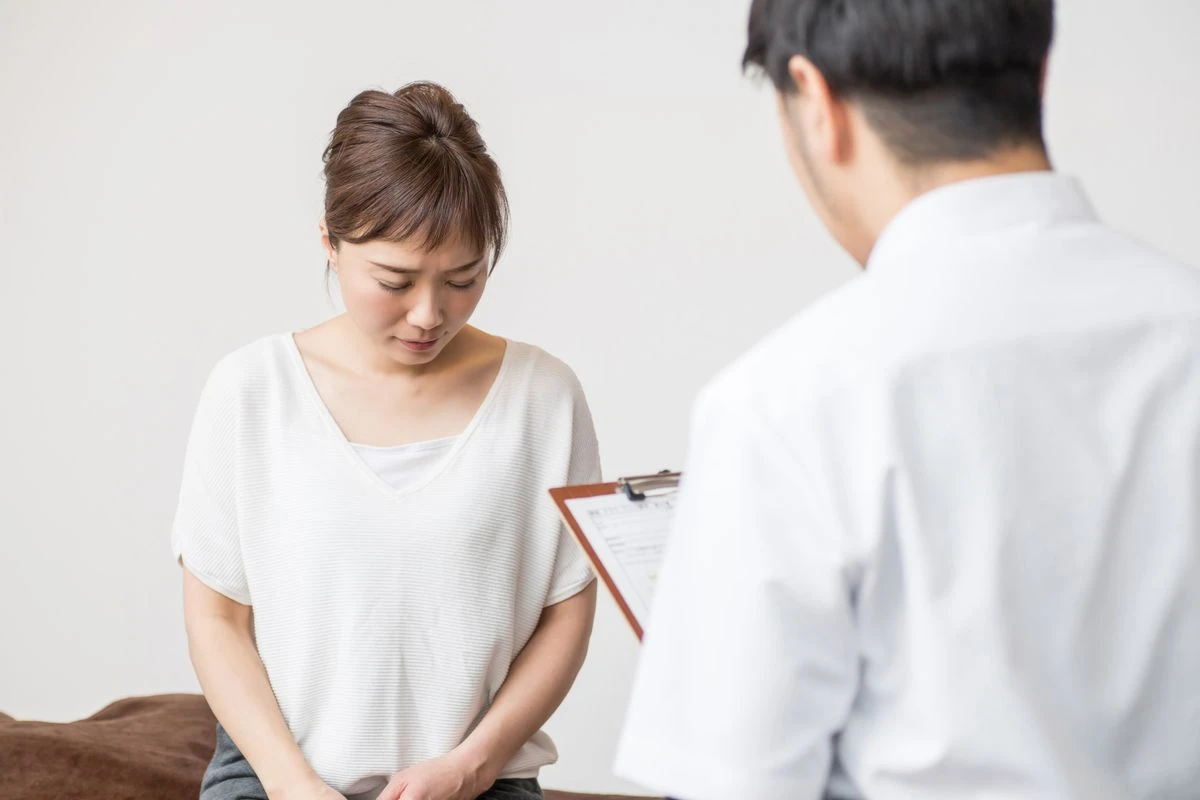 俯いたまま医師と話す女性
