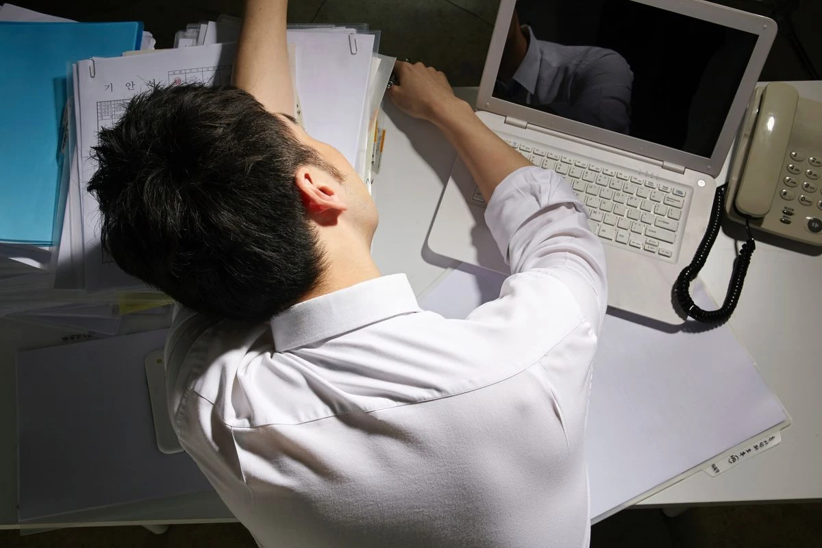 夜中、会社のデスクで突っ伏す男性