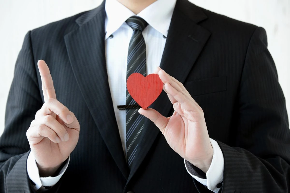 スーツを着た男性がハートのブロックを持った顔なしのウェストアップの写真