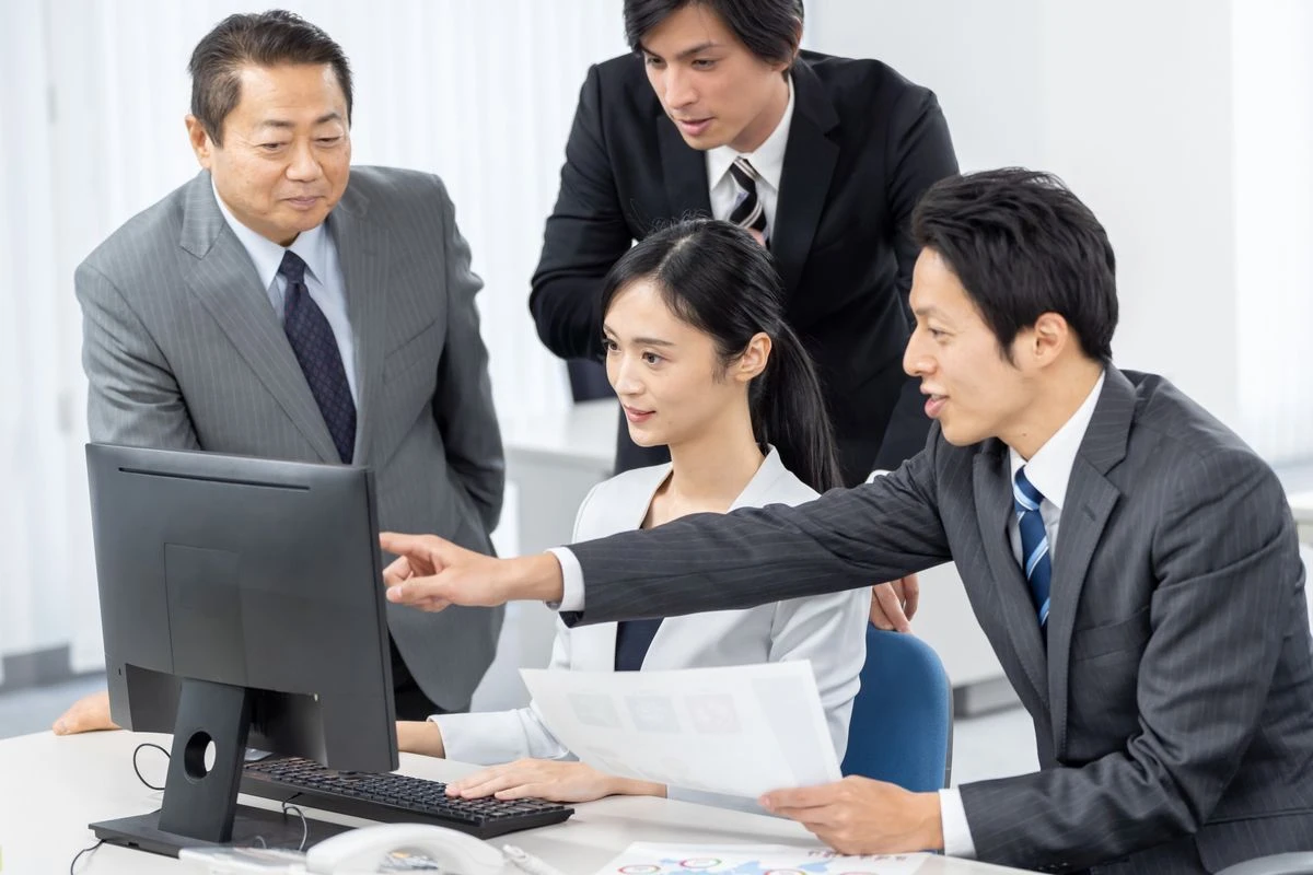 PCの画面を見ながら話し合う人たち