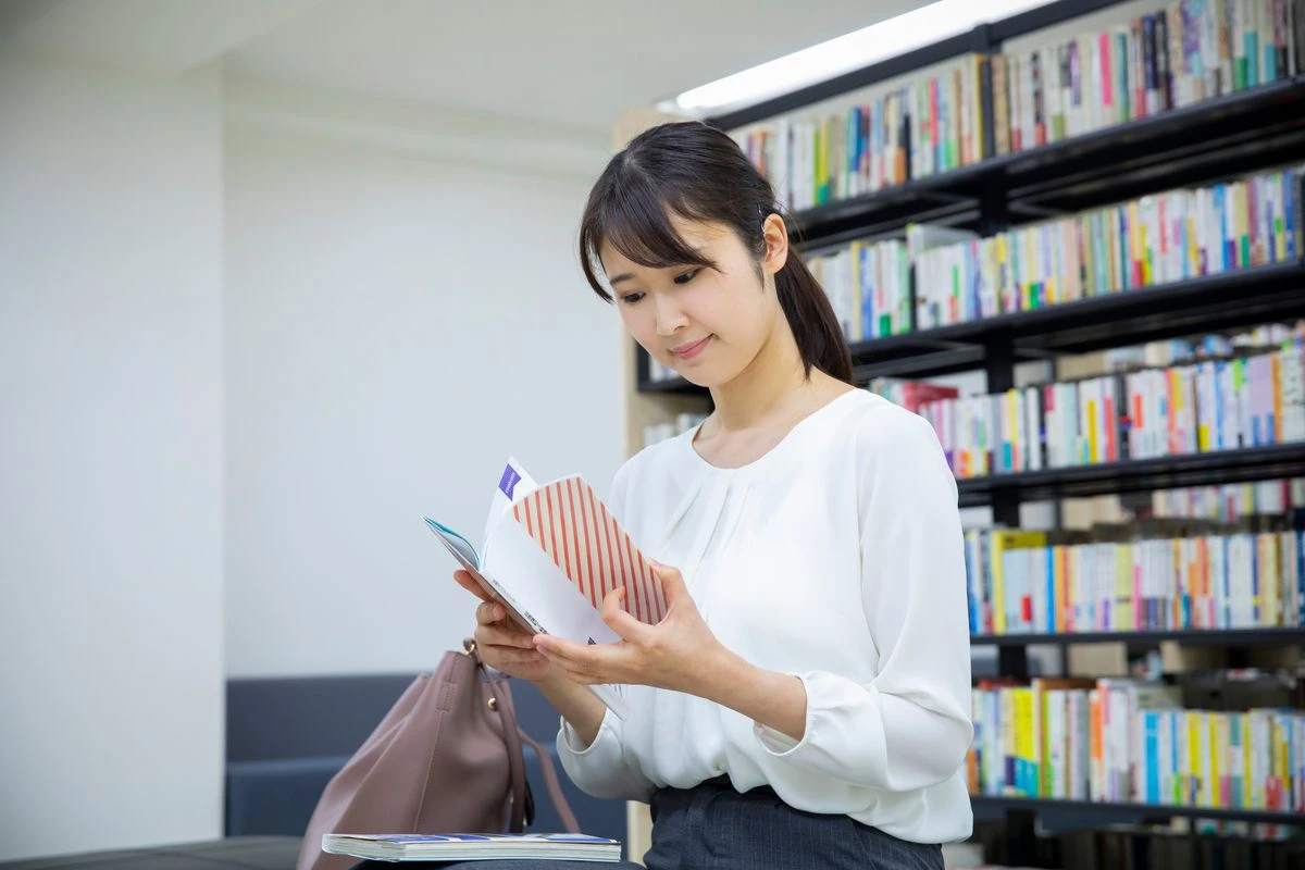 本棚の前で本を読む女性
