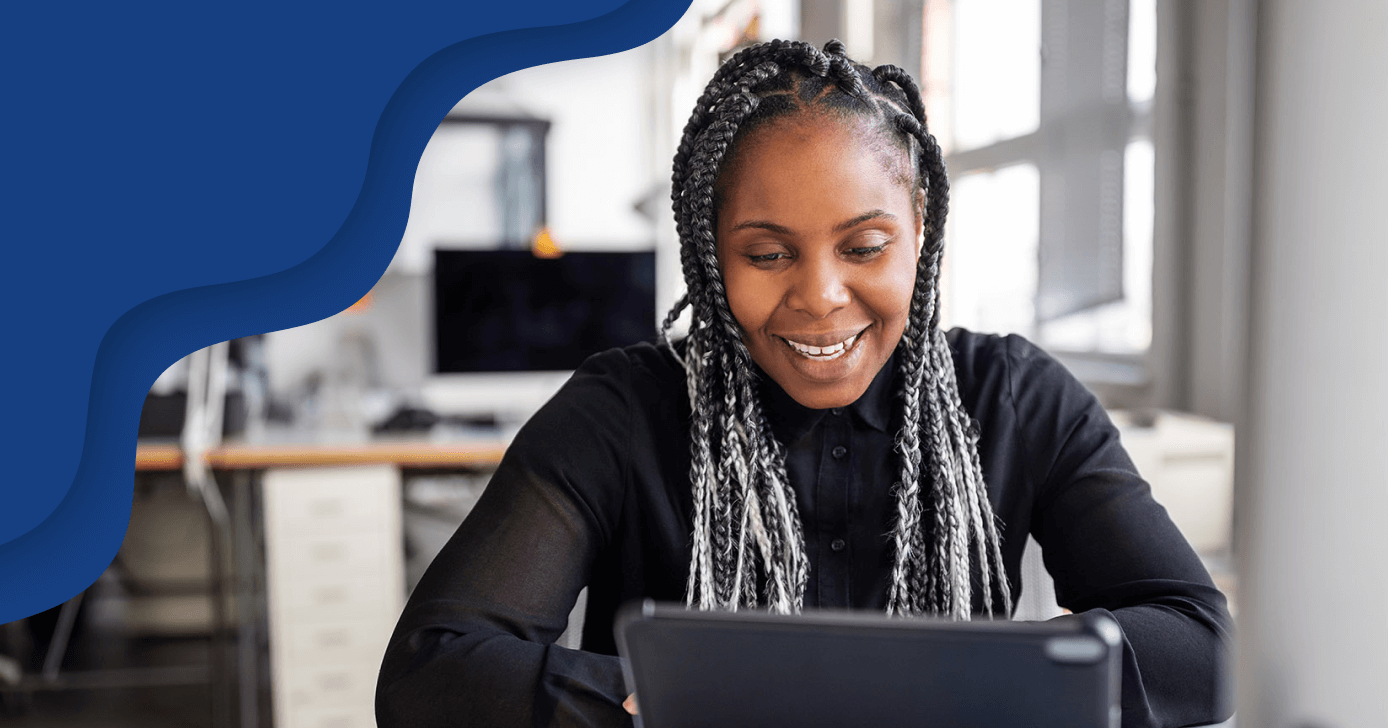 薄い、黒、灰色のドレッドヘアを持つ女性が笑顔でノートパソコンを見ている