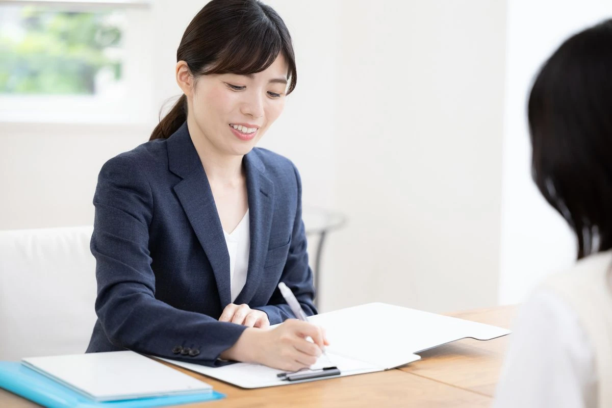 話を聞きながら字を書く女性の写真