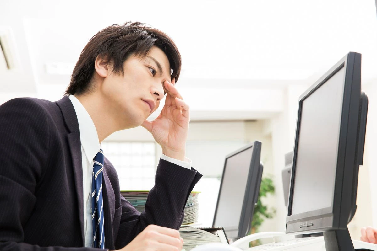 PCを見ながら頭を抱える男性