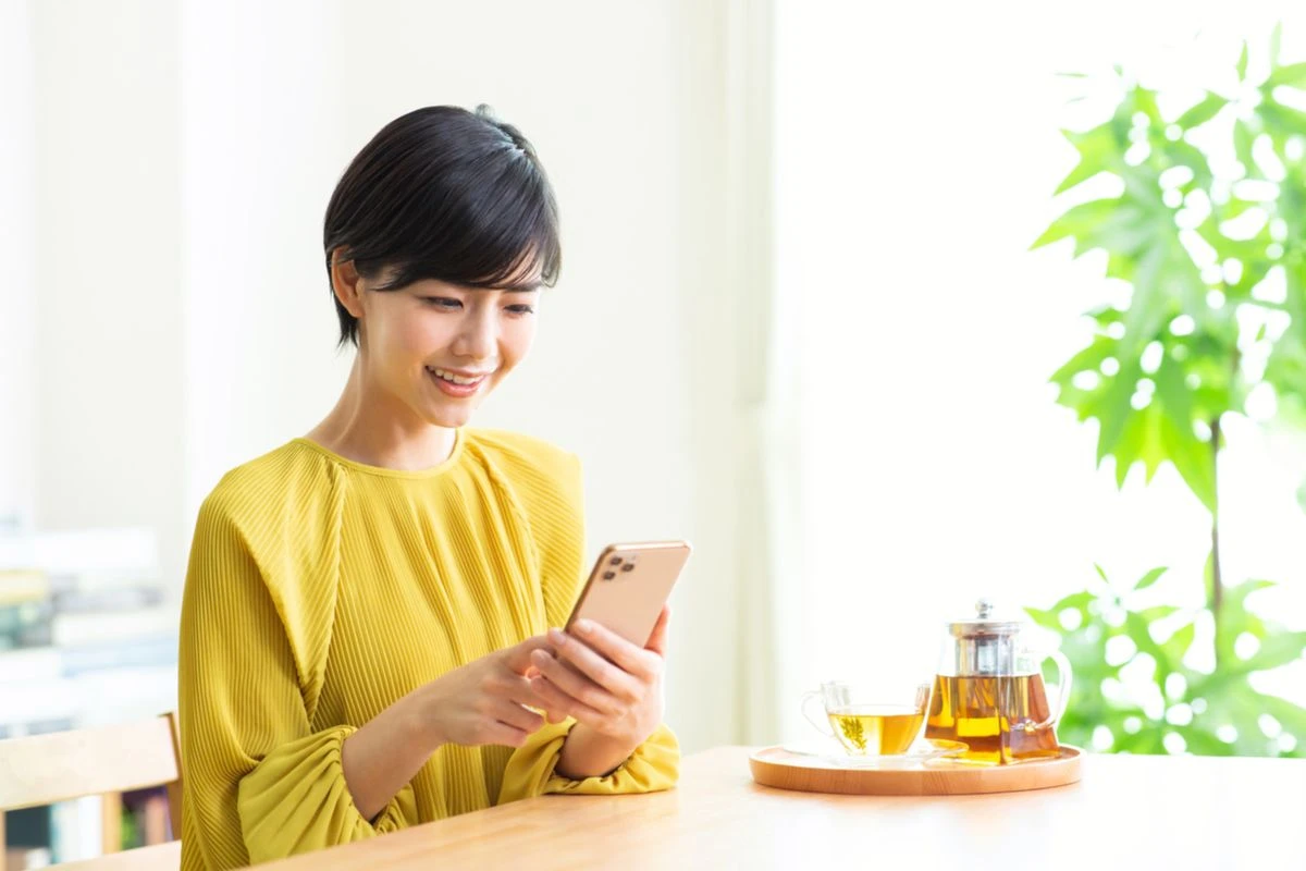 自宅でスマホを見る女性のイメージ