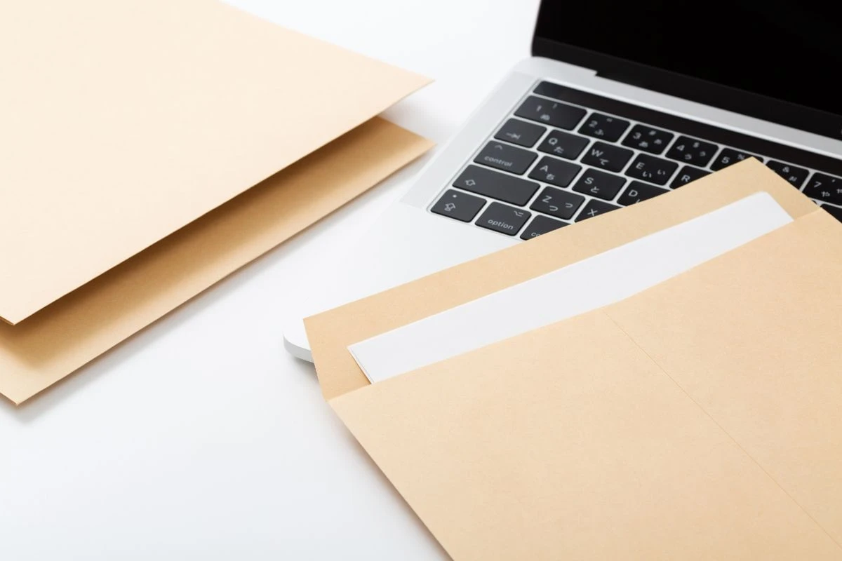 PCと書類が入った封筒の画像