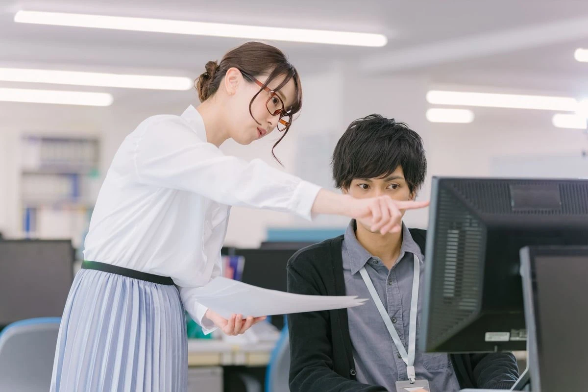 女性の上司が男性の部下に仕事を教えている様子