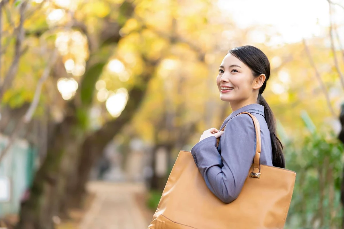 紅葉している木を背景に微笑む女性のイメージ