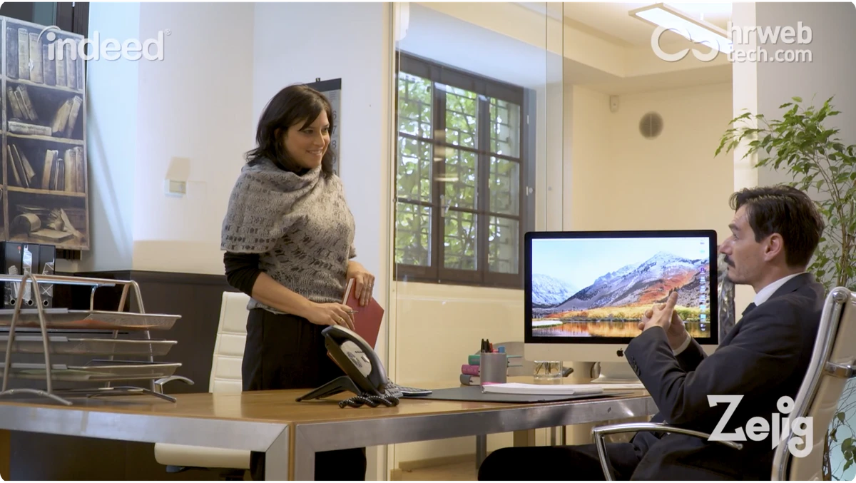 A woman stands smiling at a computer.