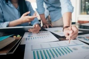 Due persone che lavorano davanti a una scrivania con grafici e tabelle