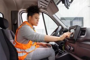 Female driver entering an address in a GPS system in delivery van. Delivery person using van GPS navigation to transport and deliver goods to the destination.
