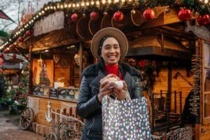 Persona in viaggio che sorride davanti allo stand gastronomico con in mano una pasticceria e una borsa della spesa