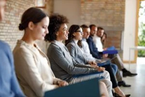 Large group of people sitting in waiting room before job interview for their potential business position.