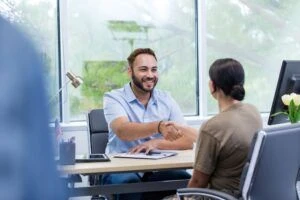 Dos personas saludándose de mano en una entrevista laboral.