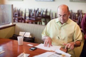 Un hombre sentado, revisando documentos.
