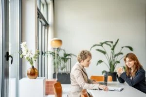 Dos mujeres en una oficina revisando documentos.