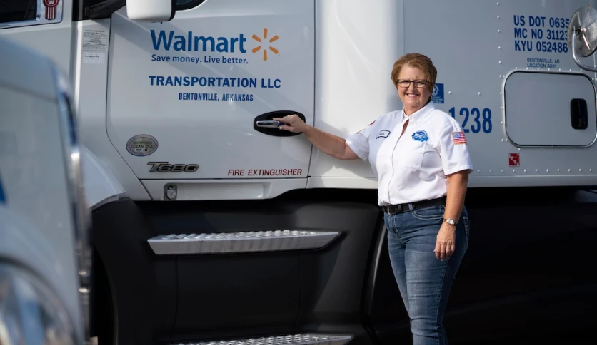 A Walmart truck driver standing next to her truck