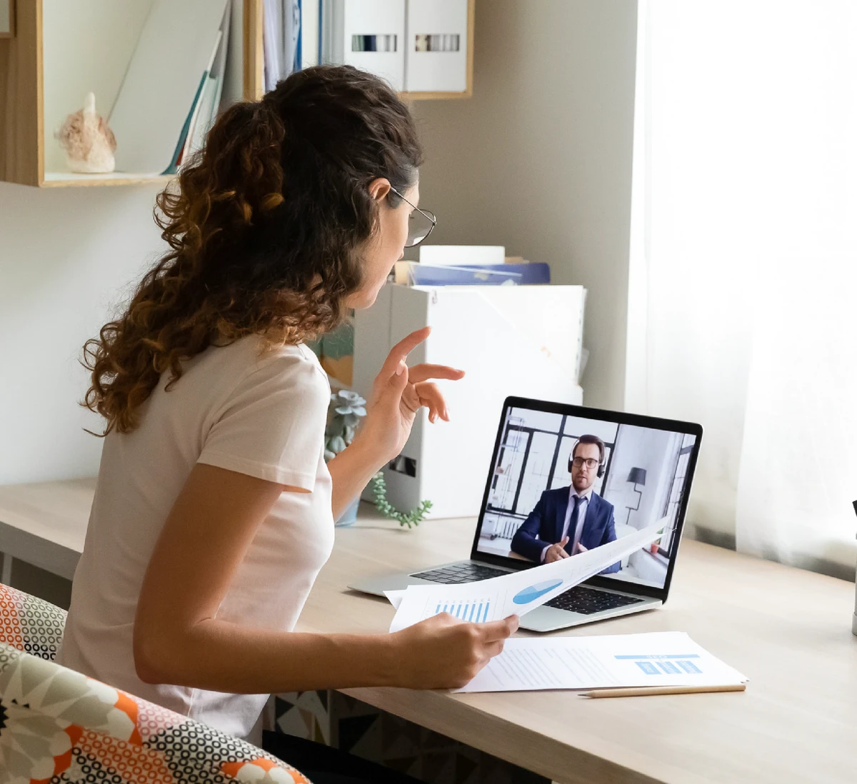 Female talking to male on a computer screen at a desk.