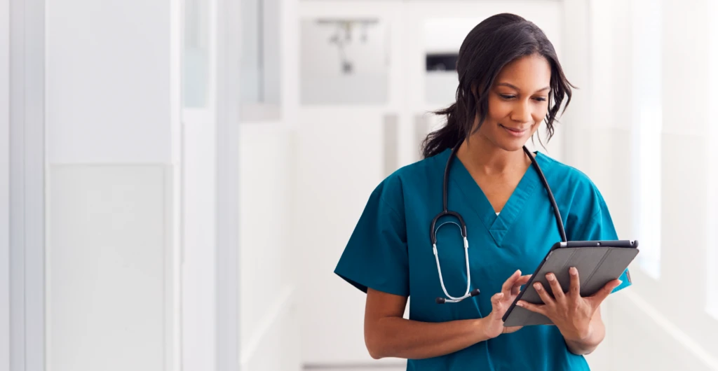 Female nurse walking looking at her chart with a stethoscope around her neck