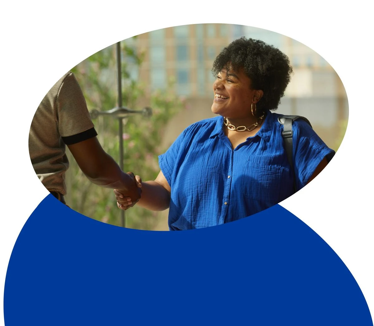 A smiling black woman shakes another persons hand.