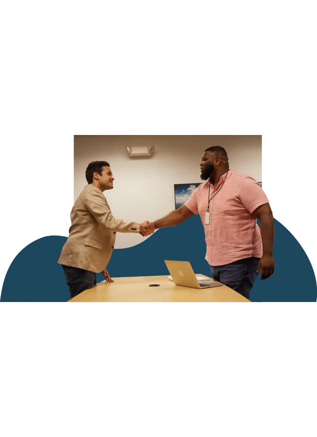 Two men shaking hands over office table.