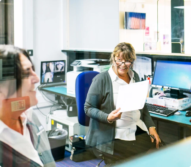 Two smiling women in an office setting at their desks
