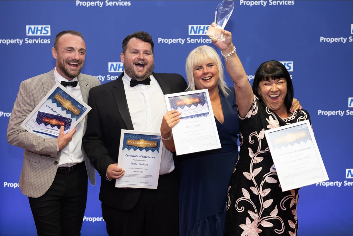 Four professionals smile and cheerfully hold NHS awards