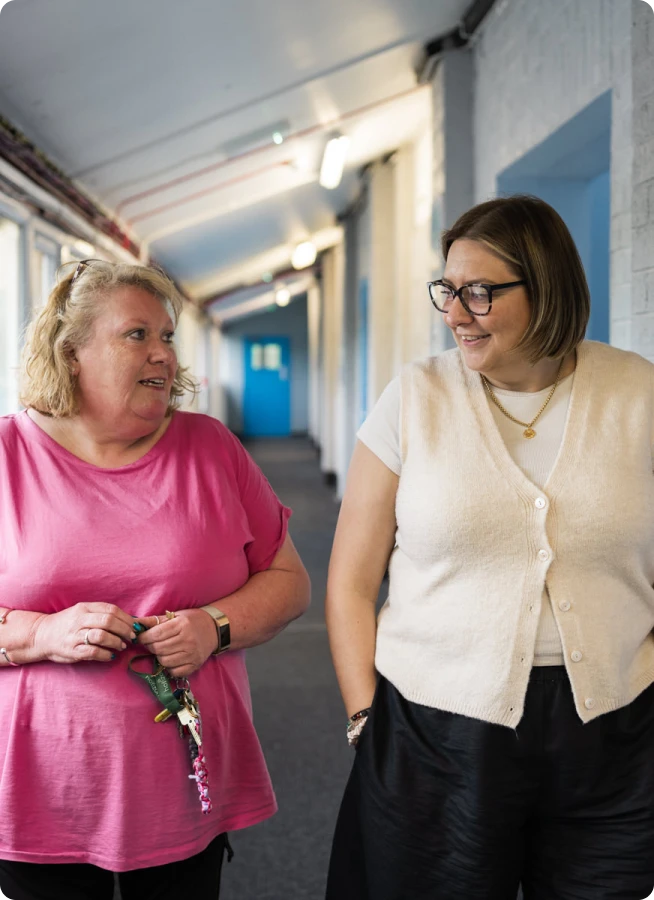 Two women walking down a hallway in conversation