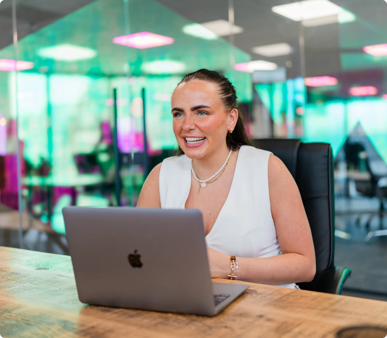 Smiling woman at a table with laptop in front of her