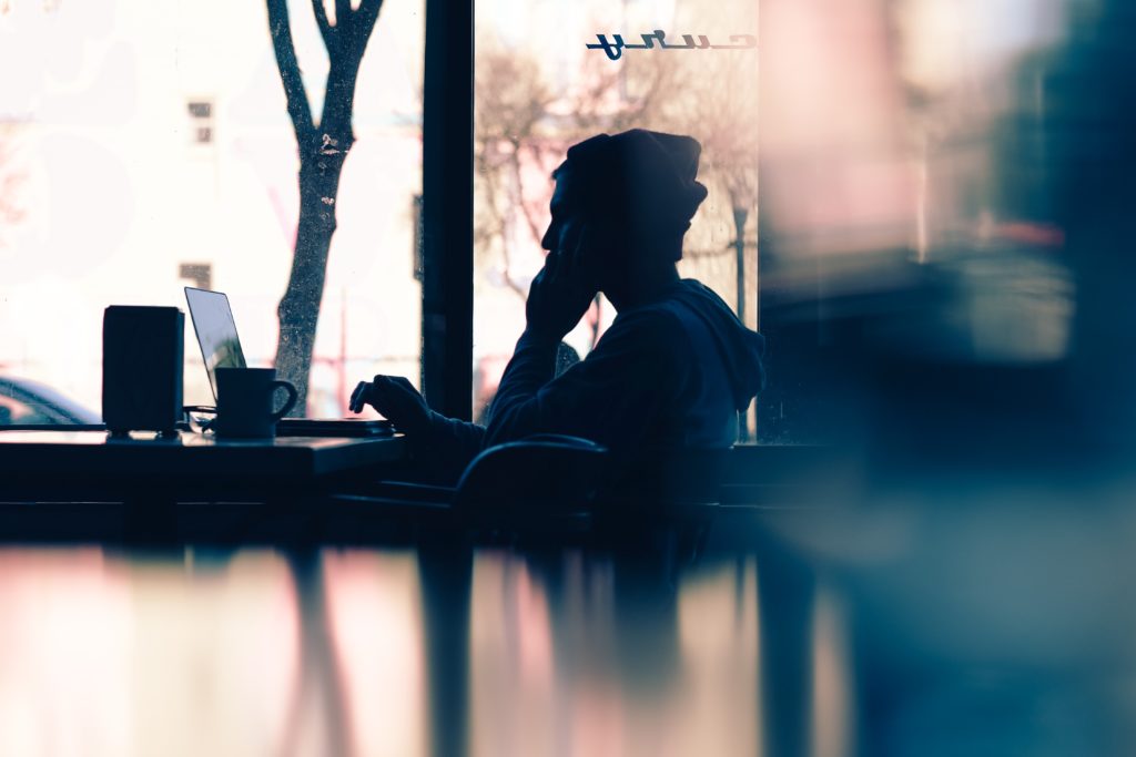 A person working remotely from a cafe with their laptop open.