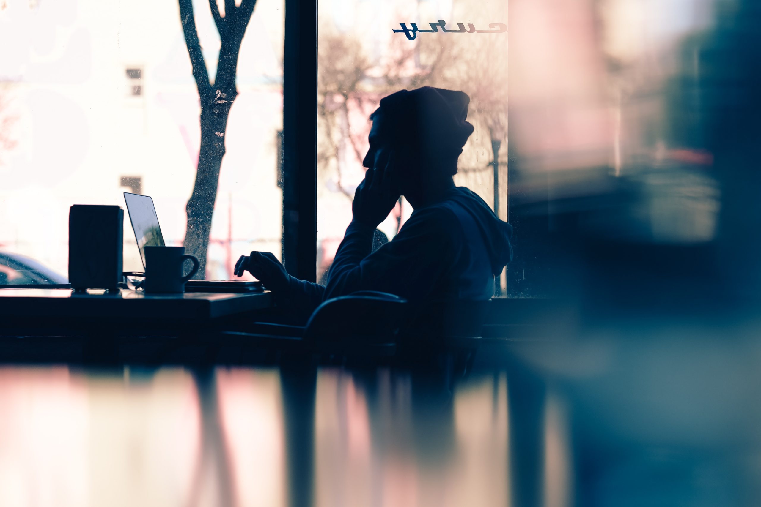 A person working remotely from a cafe with their laptop open.